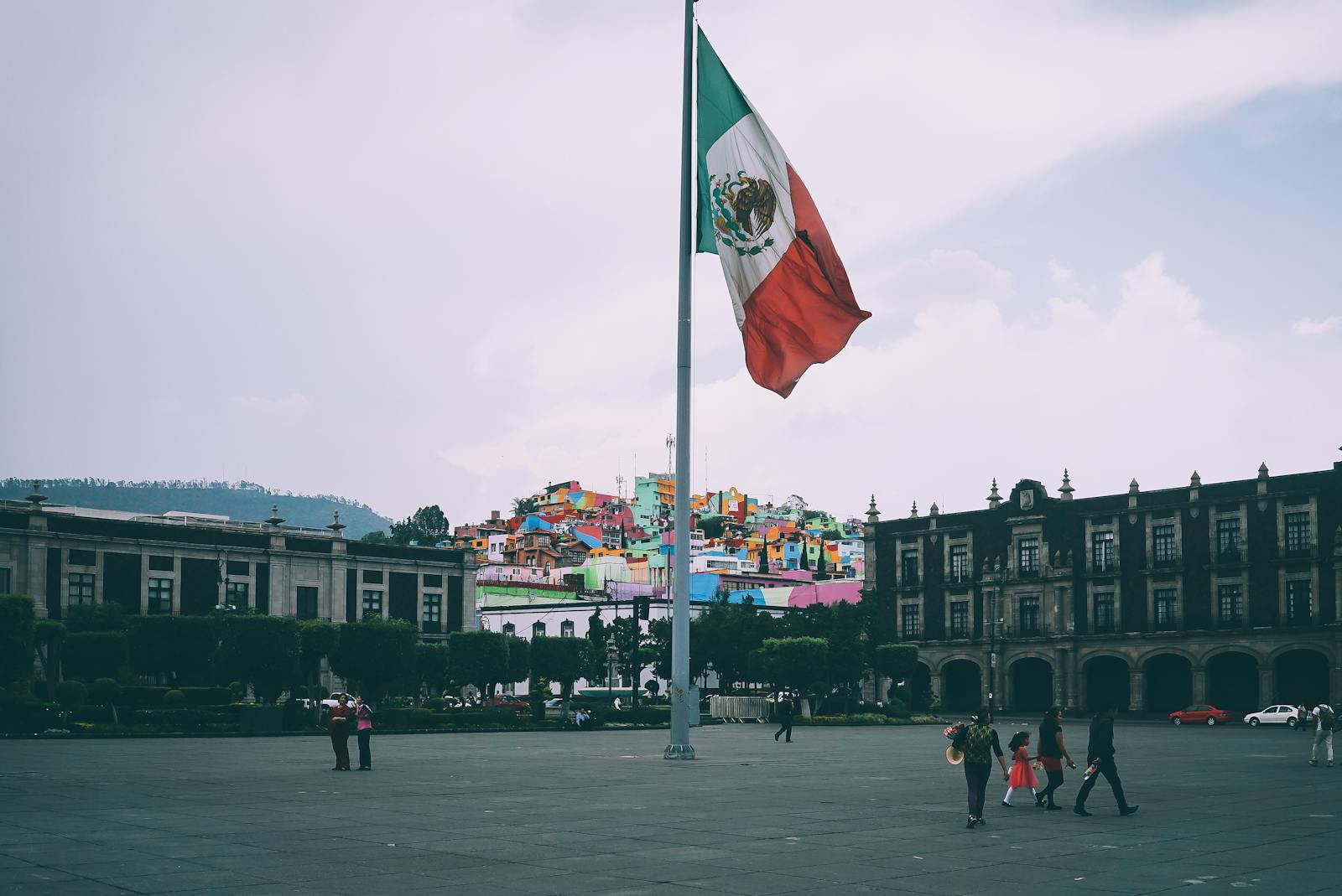 Mexico Travel, Colorful cityscape of Toluca with large Mexican flag in the foreground, vibrant buildings in the backdrop.